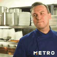 a man in a blue chef 's jacket is standing in a kitchen with plates and pots in the background and the word metro in white