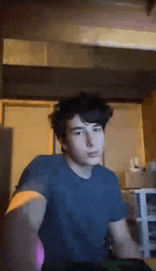 a young man in a blue t-shirt is sitting at a table .