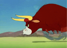 a red bull with yellow horns is running in a field .