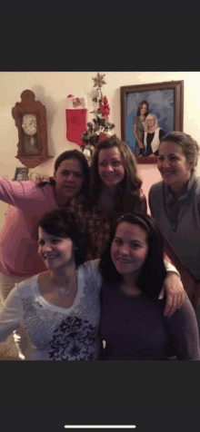 a group of women are posing for a picture in front of a clock and a christmas tree