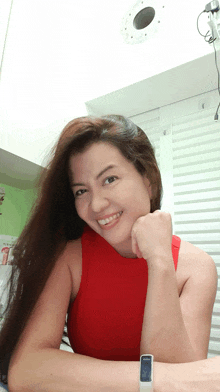 a woman wearing a red top and a white watch smiles