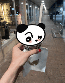 a person holding a cup of ice cream with a panda on top