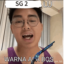 a man wearing glasses and a purple tank top is holding a gun and says sg 2 lu warna apa bos