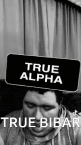 a man is wearing a sign on his head that says `` true alpha '' .