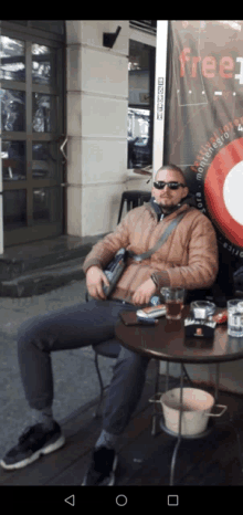 a man sits at a table in front of a sign that says " free "