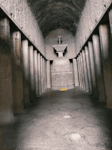 a very long hallway with columns and a statue in the middle of it