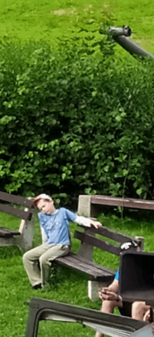 a young boy is sitting on a wooden bench in a park