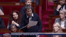 a man is giving a speech in a french parliament and the words sortez le carnet de cheques are above him