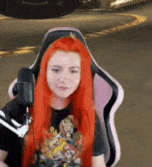 a woman with red hair is sitting in a pink chair with a microphone in front of her .