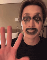 a man with black paint on his face is making a hand gesture