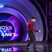 a man in a red shirt is dancing in front of a boys planet sign