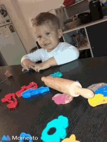 a little boy is playing with clay and a rolling pin on a table with the word momento on the bottom