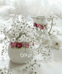 a vase filled with baby 's breath flowers sits next to a pitcher