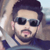 a man with a beard is wearing sunglasses and a seat belt