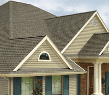 a house with a gray roof has a round window on the front