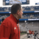 a man in a red adidas jacket stands in front of a crowd
