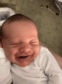 a newborn baby is smiling with its eyes closed