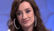 a close up of a woman wearing hoop earrings and making a funny face .