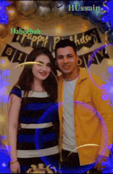 a man in a yellow jacket stands next to a woman in a blue dress at a birthday party