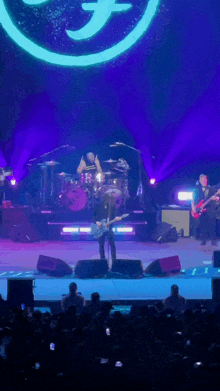 a man playing a guitar on a stage in front of a purple logo