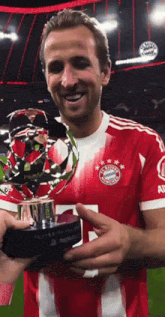 a man in a red and white striped jersey holds a trophy