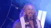 a man with long hair and a beard is wearing a robe with aew on it