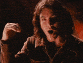 a man with long hair is waving his hand