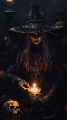 a woman in a witch costume is holding a candle in front of skulls