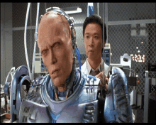 a man in a lab coat is looking at a robot with his eyes closed