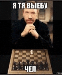 a man is sitting at a table with a chess board and a chess piece on it .