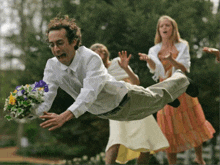 a man holding a bouquet of flowers is falling into the air