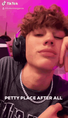 a young man with curly hair wearing headphones and a necklace .