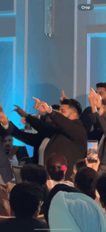 a group of people are dancing in a room with a crop button on the bottom