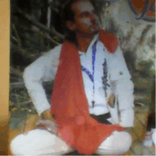 a man wearing a white shirt and a red scarf around his neck is sitting down