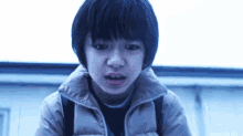 a young boy with short black hair is making a funny face .