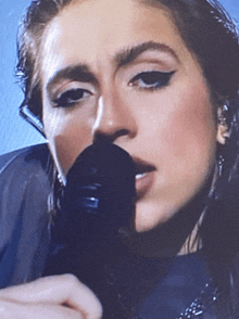 a close up of a woman singing into a microphone with a blue background