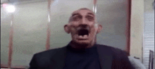 a man in a suit and tie is making a funny face with his mouth open .