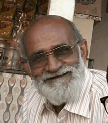 an elderly man with a beard and glasses is smiling for the camera .