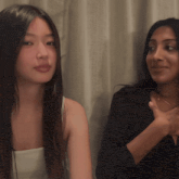 two women are sitting next to each other and one has a tattoo on her arm
