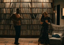 a man and a woman are dancing in a living room in front of a wall of books .