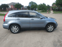 a blue honda crv is parked on a concrete driveway