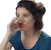 a woman in a blue shirt is drinking a glass of wine