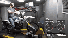 a man sits on a dirt bike in front of a machine that says engine rpm