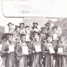 a group of graduates are posing for a picture in front of a sign that says cosmetology university