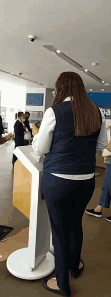 a woman in a blue vest is standing in front of a sign that says ' ba '