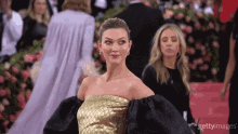 a woman in a gold and black dress is standing on a red carpet with getty images written on the bottom