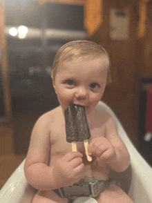 a baby in a high chair is eating a chocolate popsicle