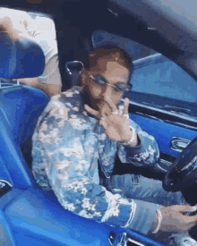 a man in a blue jacket is sitting in a blue car