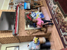 a little girl laying on a brick fireplace in front of a flat screen tv