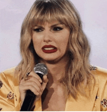 a woman in a yellow jacket is holding a microphone and making a face .